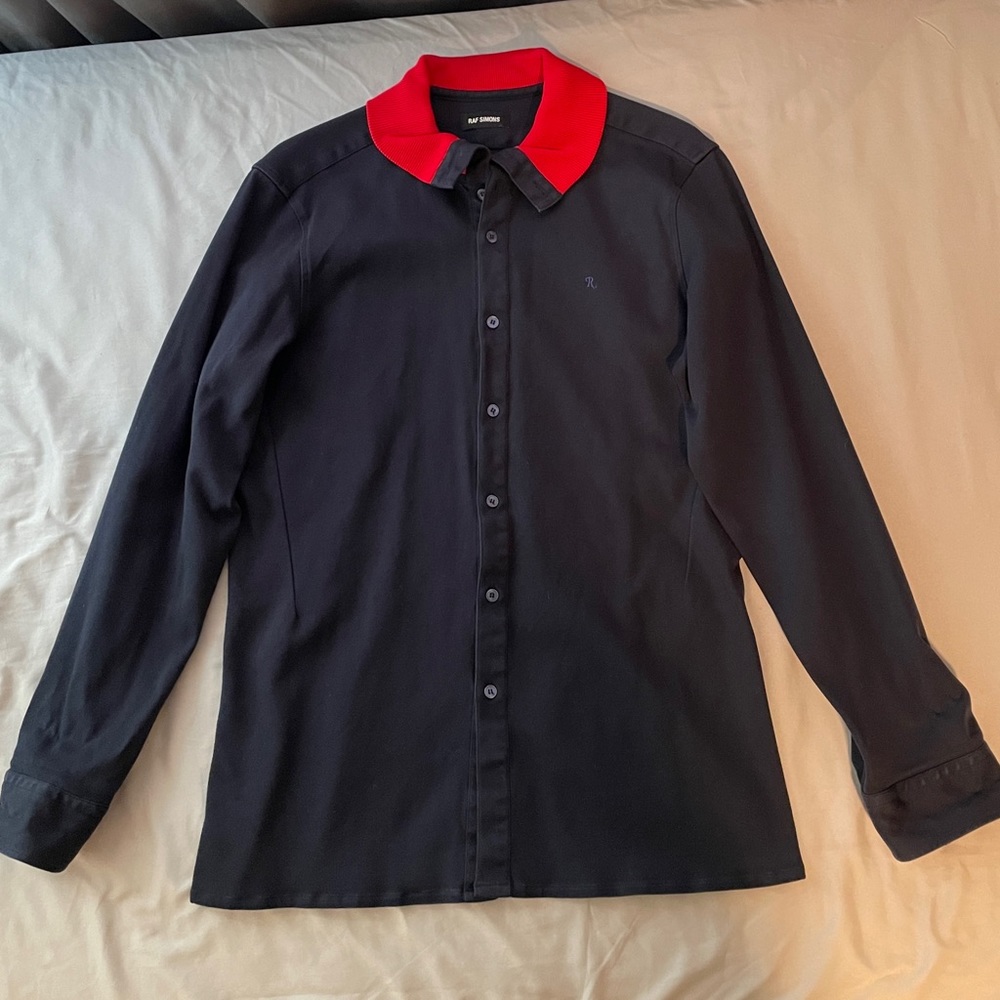 RAF SIMONS navy blue button-up shirt with red rib collar.